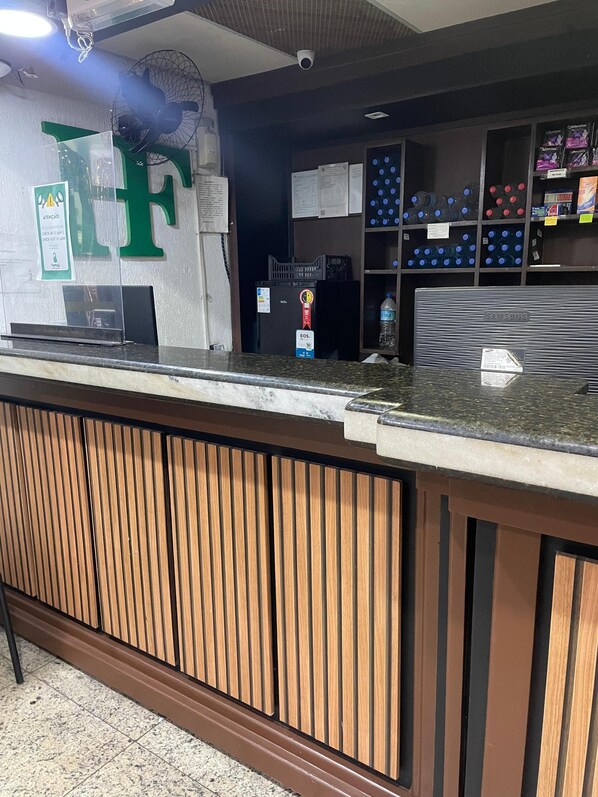 A reception desk with a wooden panel design, a Samsung monitor, and a water dispenser.