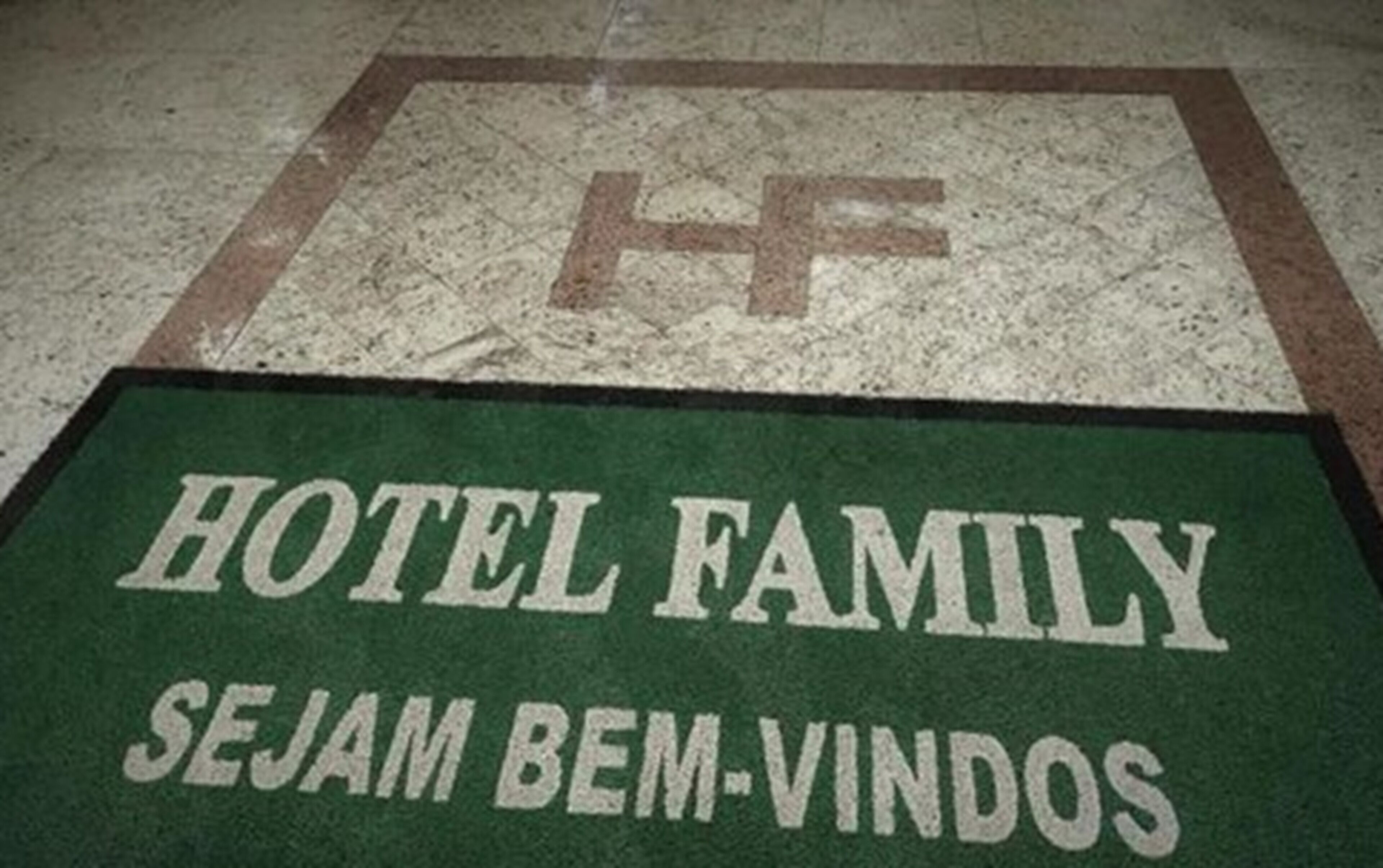A green mat with "HOTEL FAMILY" and "SEJAM BEM-VINDOS" text.
