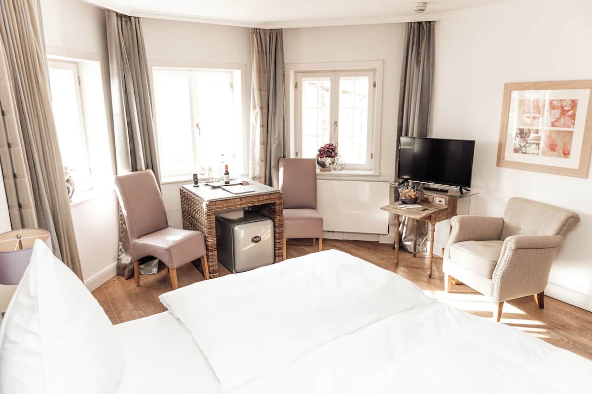 A hotel room with a bed, a desk, a television, and two chairs.