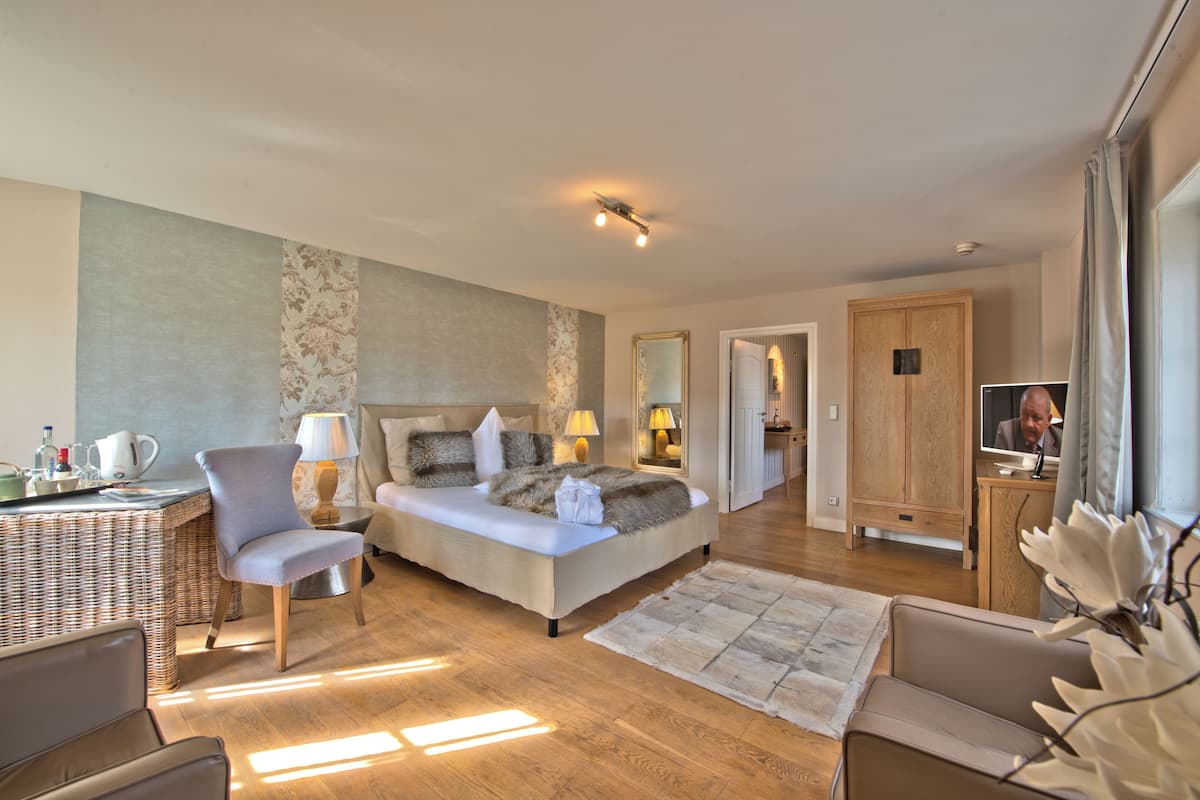 A modern hotel room with a bed, a chair, a desk, and a television.