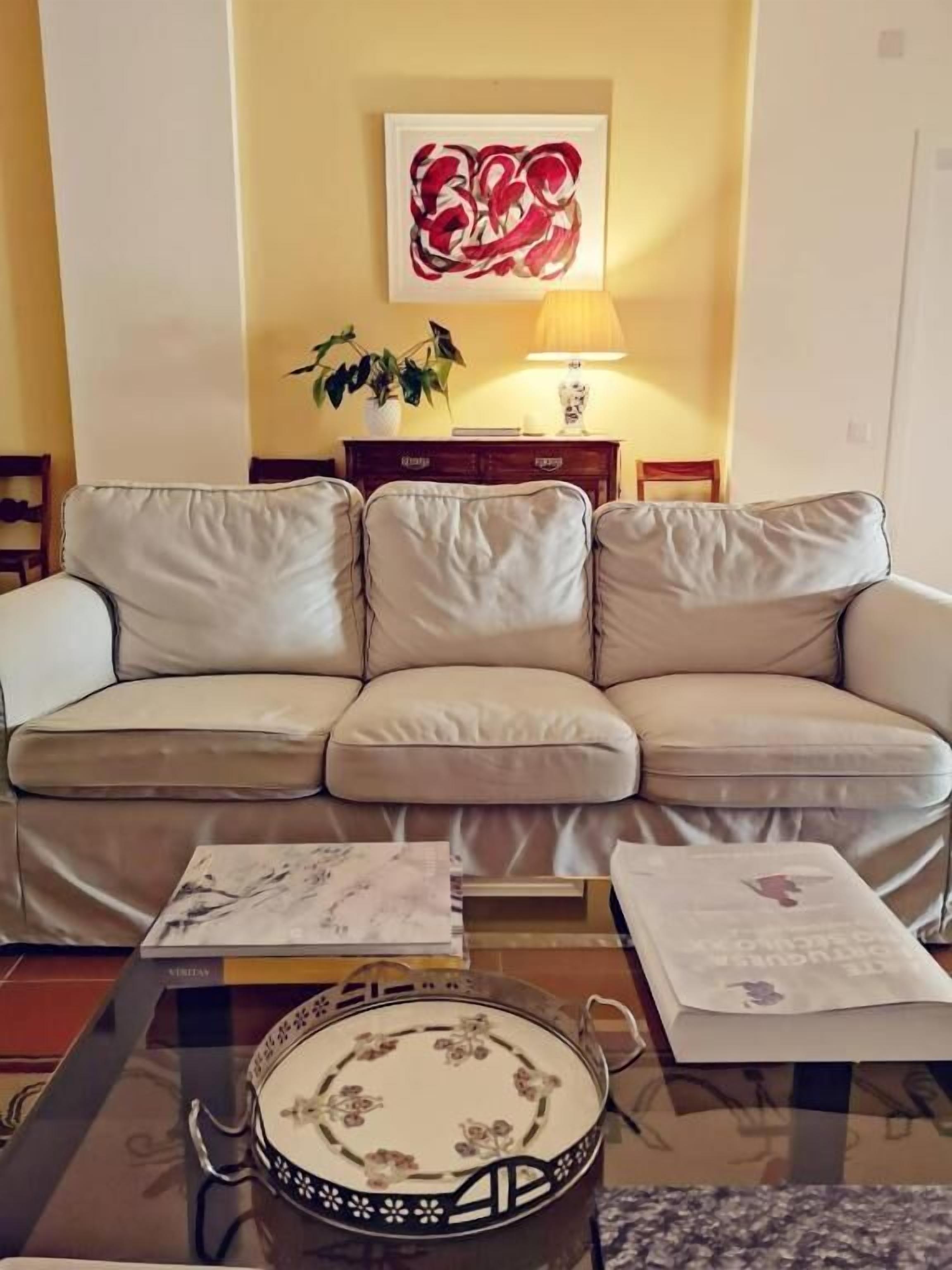 Una sala de estar con un sofá color beige, una mesita de centro con adornos y una lámpara de pared.