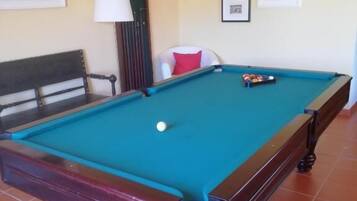 A pool table with balls, a lamp, and framed pictures on the wall.
