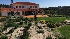 A two-story house with a red-tiled roof and a large front lawn. - Casa do Alfaro (Azambuja)