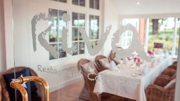 A restaurant with a glass wall displaying the name 'Riva'.