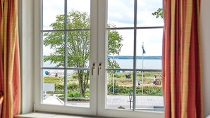 Ein Hotelzimmer mit großem Fenster und Blick auf Strand und Meer.
