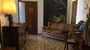 A living room with a mosaic floor, a sofa, a desk with a laptop, a lamp, and a painting on the wall. - Ca' Barbaria (Venice)