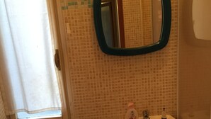 A bathroom with a toilet, sink, mirror, and a small trash bin. - Ca' Barbaria (Venice)