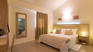 A hotel room with a large bed, bedside tables, a mirror, and a window with curtains.