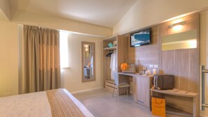 A hotel room with a bed, a desk with a chair, a TV mounted on the wall, and a wardrobe. - Palazzo Ruschioni Boutique Hotel (Camerano)
