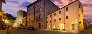 A hotel with multiple floors, a parking area, and a street view at dusk.