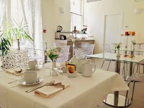 A dining area with a glass table set for four, surrounded by intricately designed chairs. - Palazzo Ruschioni Boutique Hotel (Camerano)
