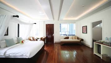 Amplia habitación de hotel con una cama grande, un sofá, una mesita y vistas al exterior.
