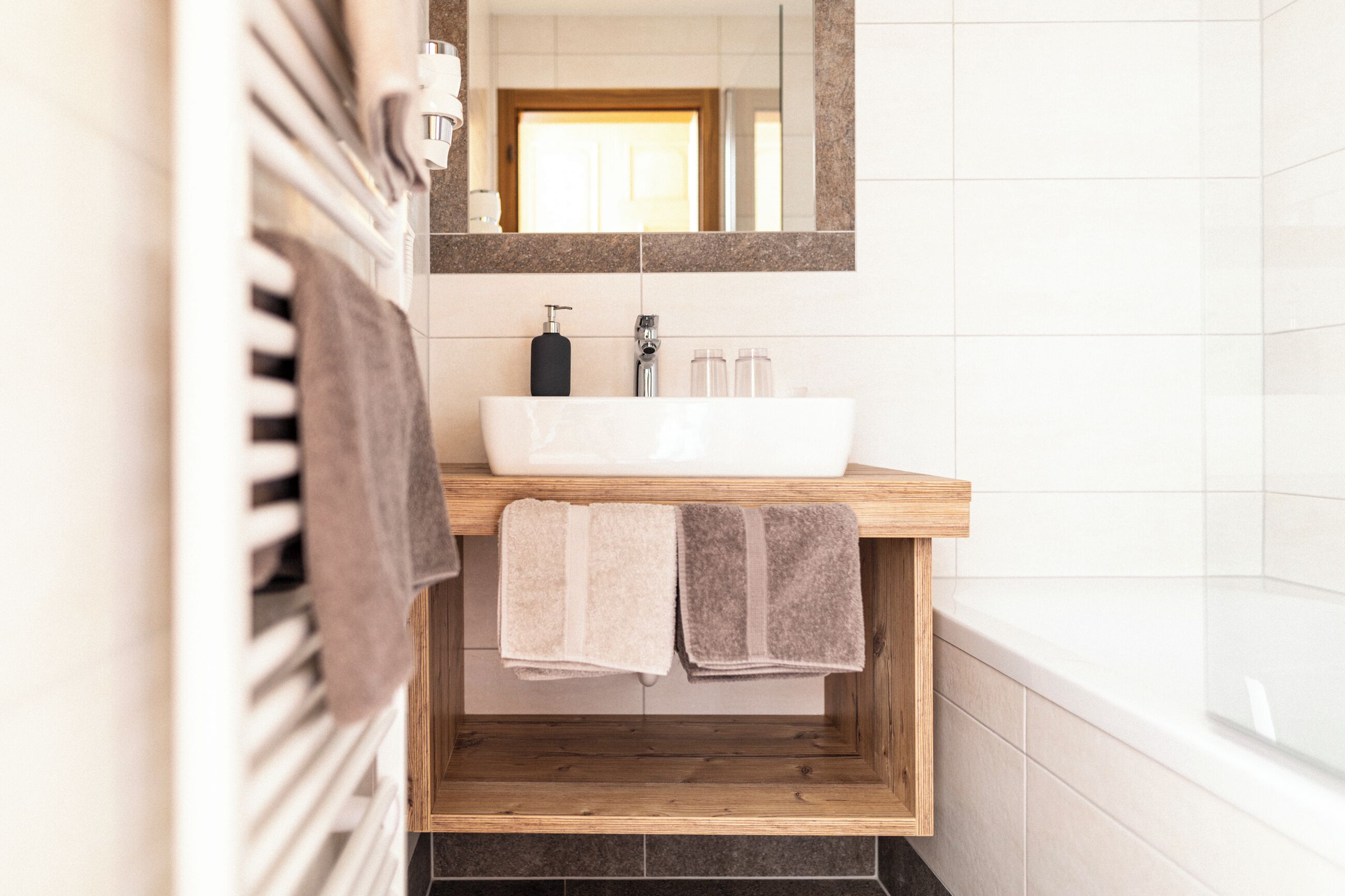 A bathroom with a wooden vanity, a white sink, and a mirror above it.