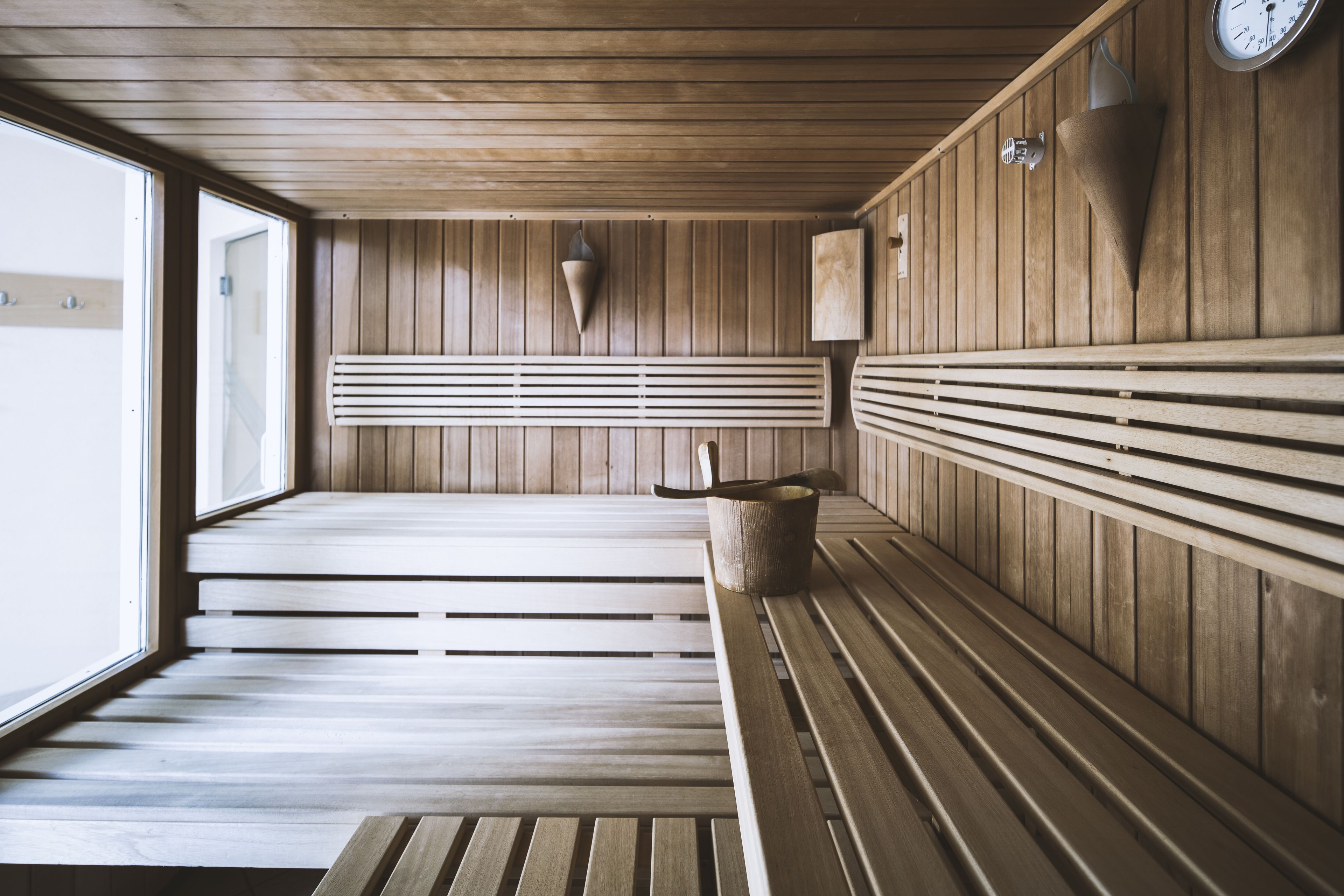 A sauna with wooden benches, a slatted bench, and a wall-mounted clock.