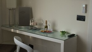 Eine moderne Küche mit einer Glasarbeitsplatte, einem weißen Stuhl, einer Weinflasche und einer kleinen Schale mit Obst.