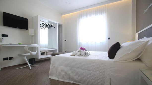 Ein modernes Hotelzimmer mit Bett, Schreibtisch, Stuhl, Fernseher und einem großen Fenster.