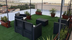 Eine Dachterrasse mit Gartenmöbeln, Blumentöpfen und Blick auf Stadt und Wasser.