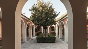 A courtyard with a central tree, surrounded by arches and a tiled floor. - Villa Veneziano Lefkada (Lefkada)