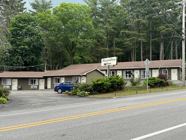 A motel named 'Hamilton Inn' with a two-story structure, a parking area, and a blue car parked in front. - Hamilton Inn (Sturbridge)