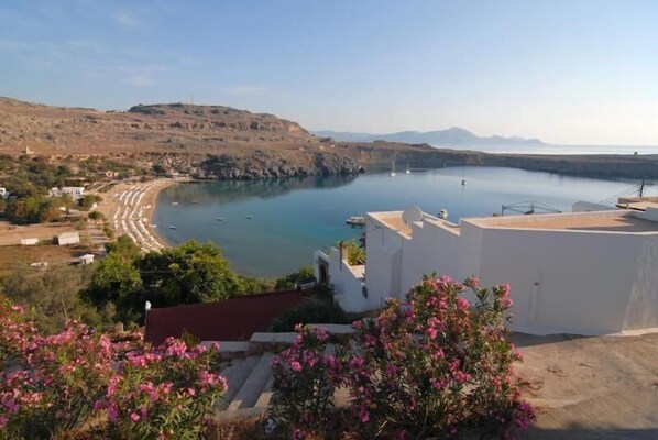 A coastal view with a beach, boats, and a white building with a red roof. - Popi Studios (Rhodes)