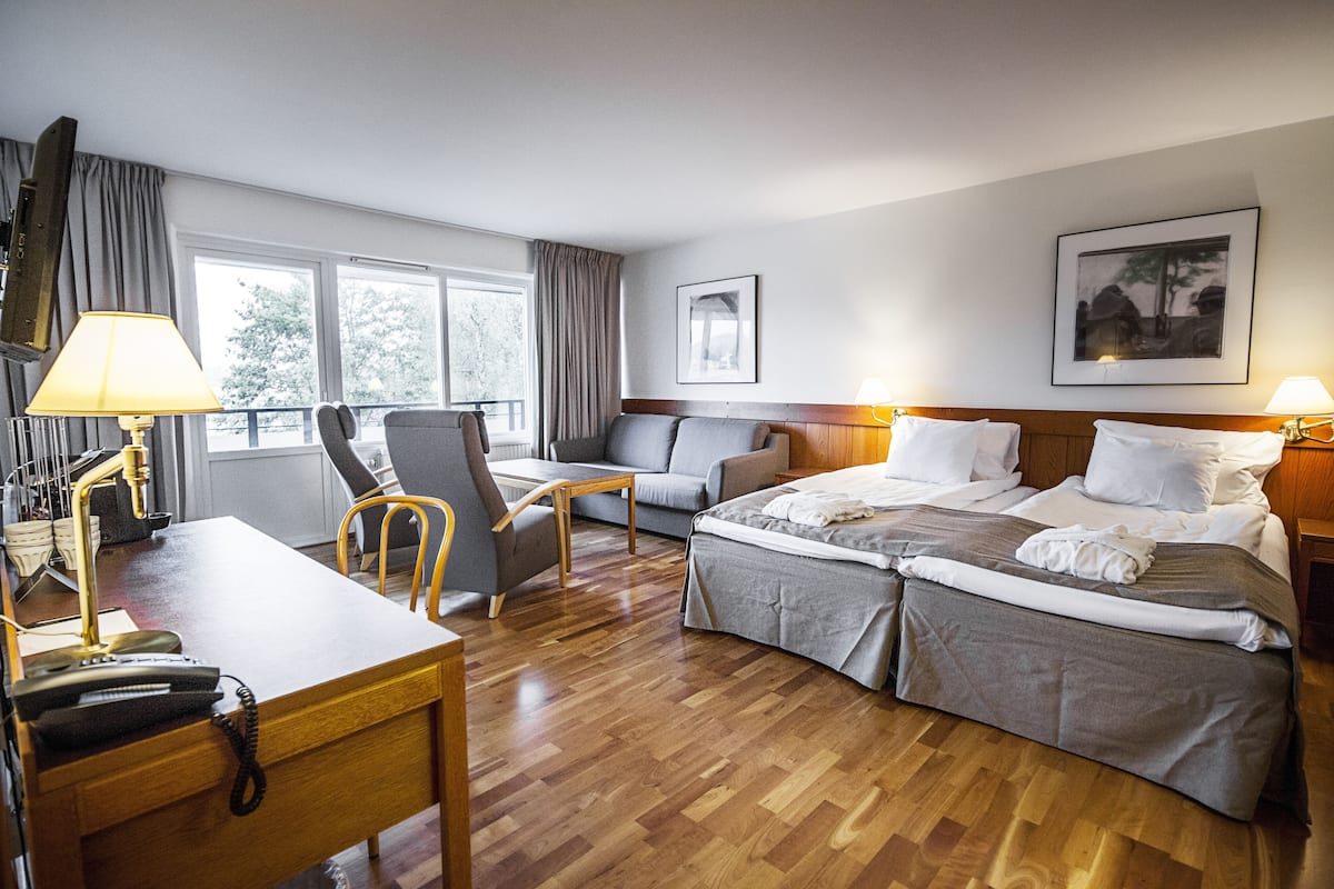 A hotel room with a bed, a desk, a chair, a TV, and a window.