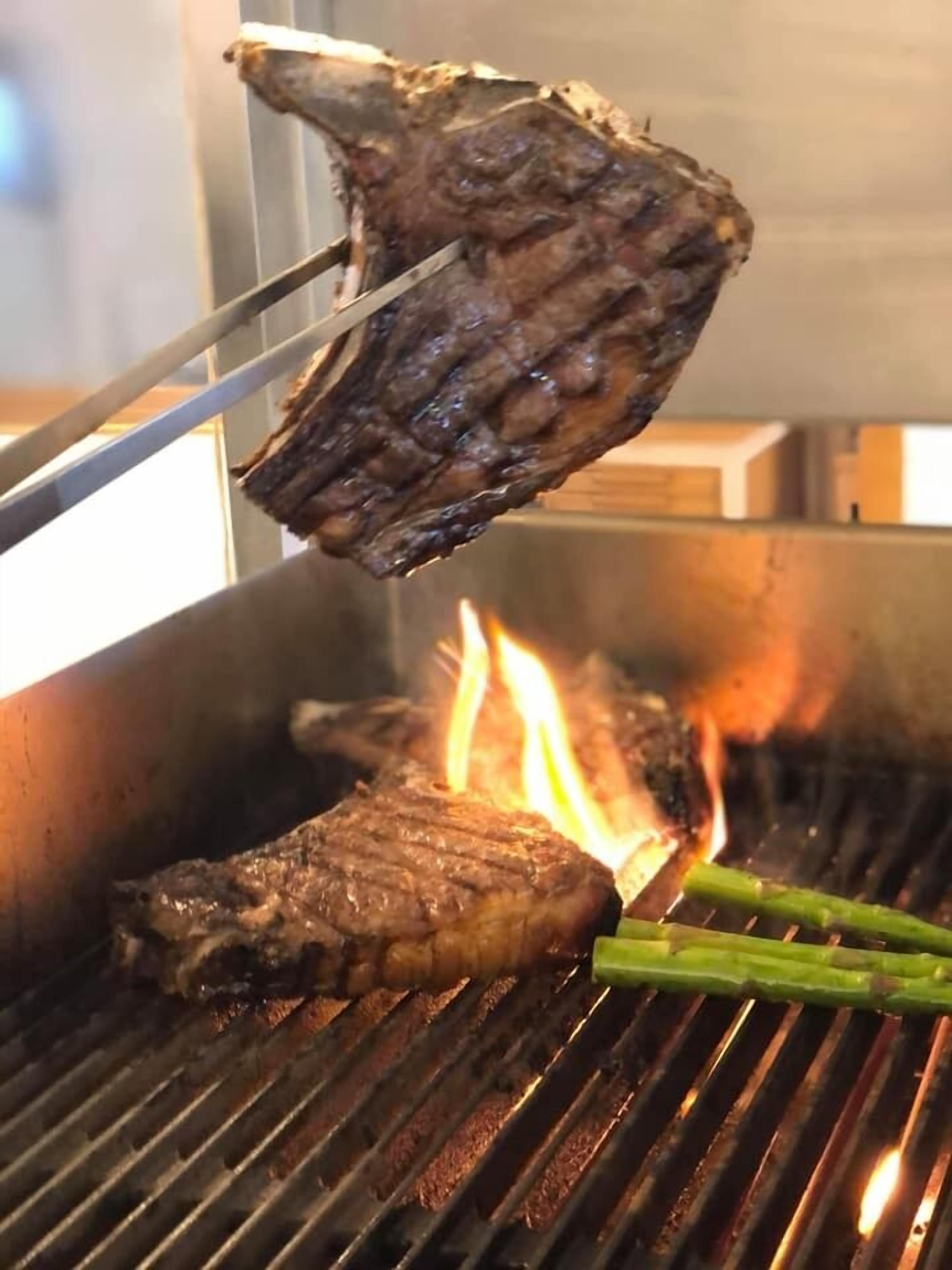 Un filete asándose en una parrilla con llamas visibles.