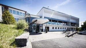 Un edificio moderno con entrada cubierta, zona de estacionamiento y bicicletas aparcadas afuera.