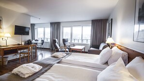 Habitación de hotel con dos camas, un escritorio, una silla, una mesa y un televisor.