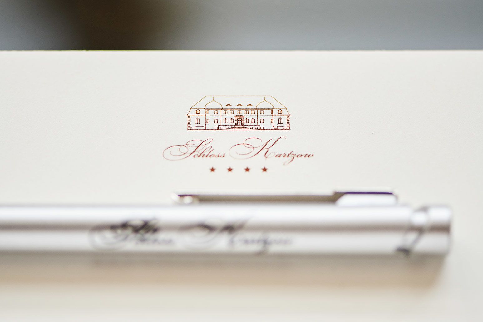 Caneta com etiqueta e desenho de um edifício, com o texto 'Schloss Kartzow' abaixo.