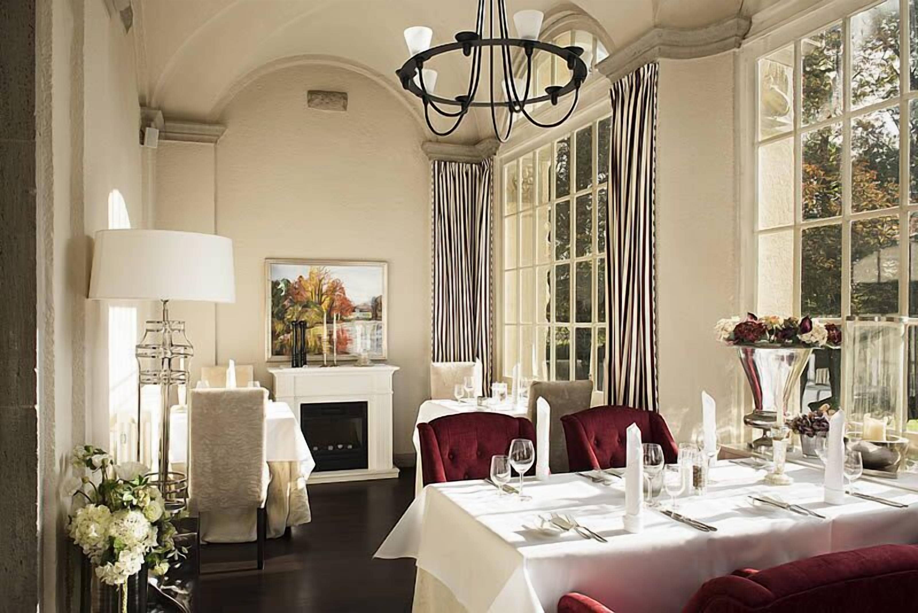A formal dining room with a fireplace, elegant table settings, and large windows.