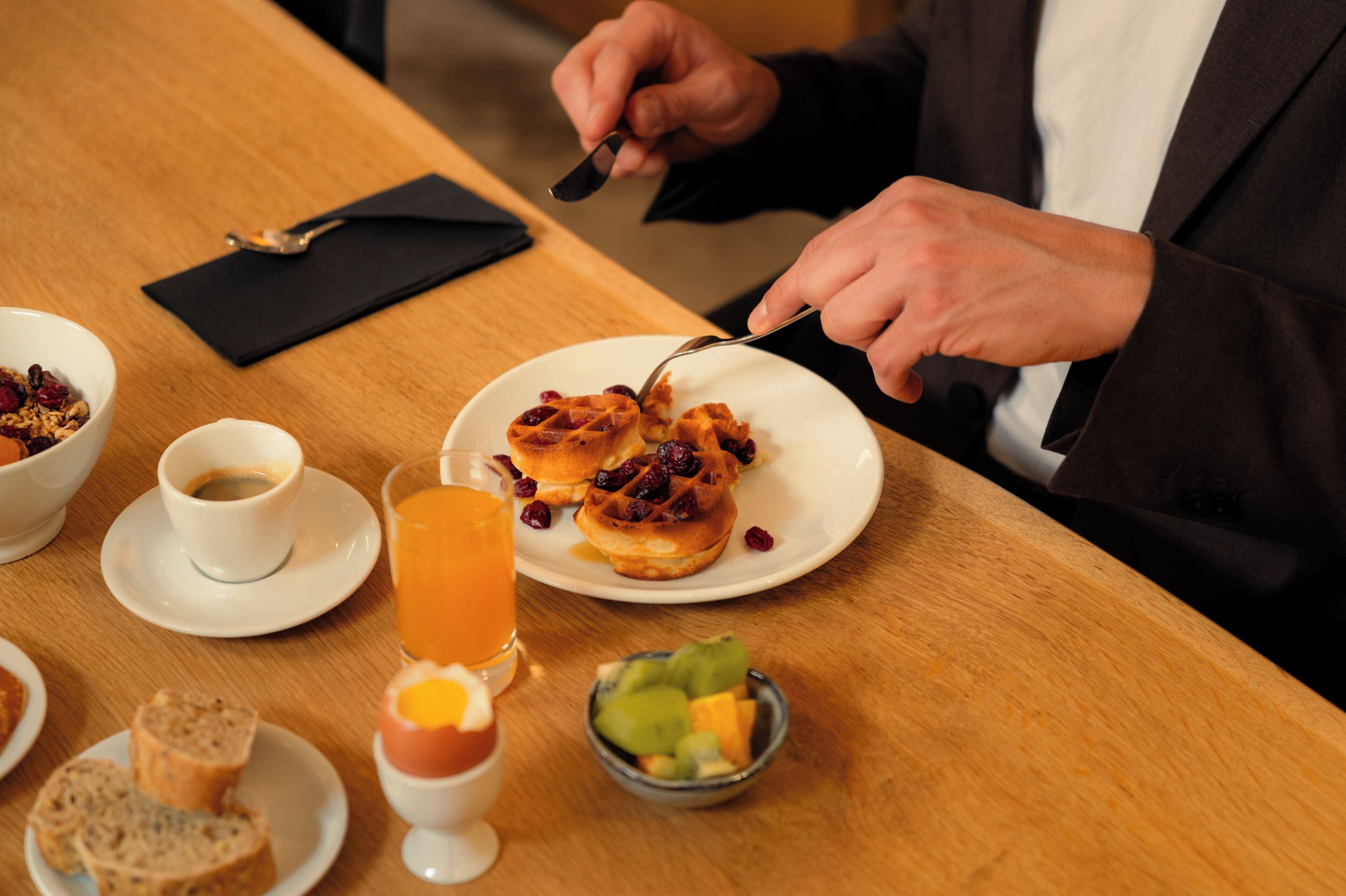 A breakfast setting with a plate of waffles, a cup of coffee, and a glass of orange juice.