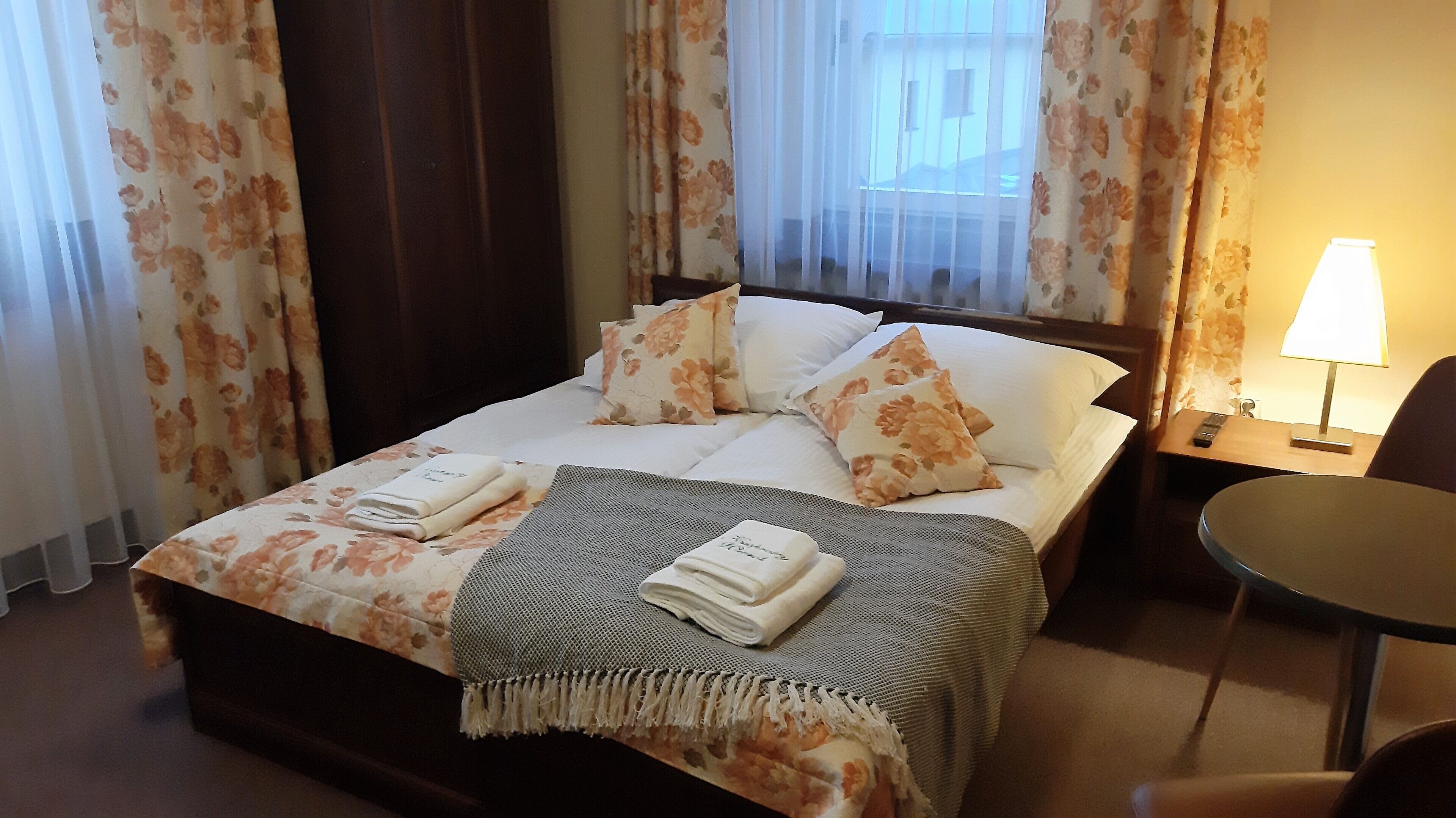 Een hotelkamer met een bed, een nachtkastje met een lamp en een stoel.