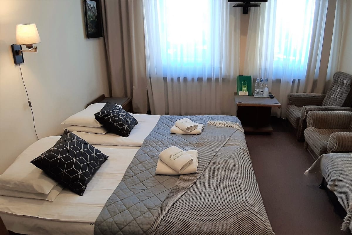 A hotel room with two beds, a sofa, a small table, and a lamp.