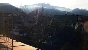 Uitzicht vanaf een balkon op een bergachtig landschap, met gebouwen op de voorgrond.
