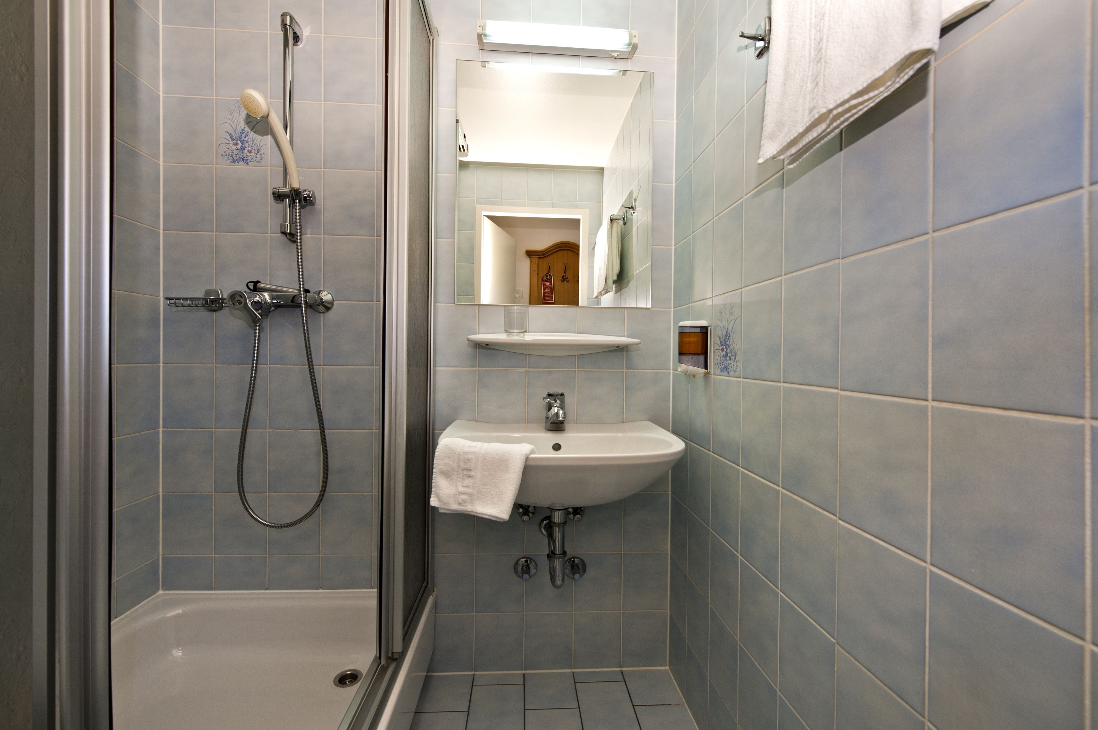 A bathroom with a shower, sink, and mirror.