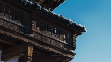 Eine Holzchalet mit mehreren Balkonen vor einer verschneiten Berglandschaft.