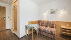 A small, cozy room with a wooden door, a bench, and a sofa. There are two wall-mounted lights and a framed picture on the wall. - Gasthof Batzenhaeusl (Seefeld in Tirol)