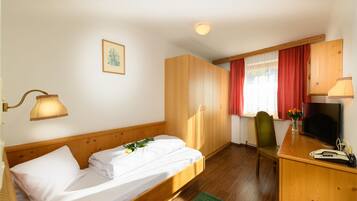 Ein Zimmer mit einem Bett, einem Schreibtisch, einem Sessel, einem Fernseher und einer Lampe.