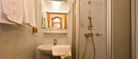 Un baño con lavamanos, espejo y ducha.