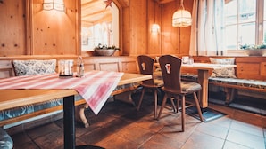 A cozy wooden interior with a long table and benches, warm lighting, and a star decoration. - Gasthof Batzenhaeusl (Seefeld in Tirol)