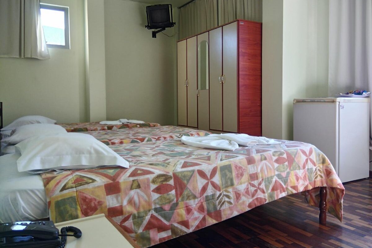 A hotel room with a bed, a wardrobe, a television, and a small refrigerator.