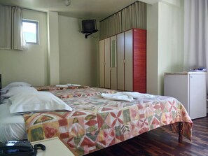 A hotel room with a bed, a wardrobe, a television, and a small refrigerator.