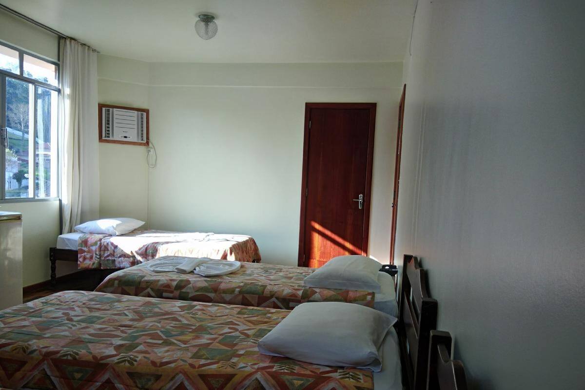 Une chambre d’hôtel avec deux lits, une fenêtre, une porte et un climatiseur fixé au mur.