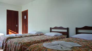 Quarto com duas camas de solteiro, cada uma com cabeceira de madeira e colcha estampada. Há uma porta com uma placa e um lustre no teto.