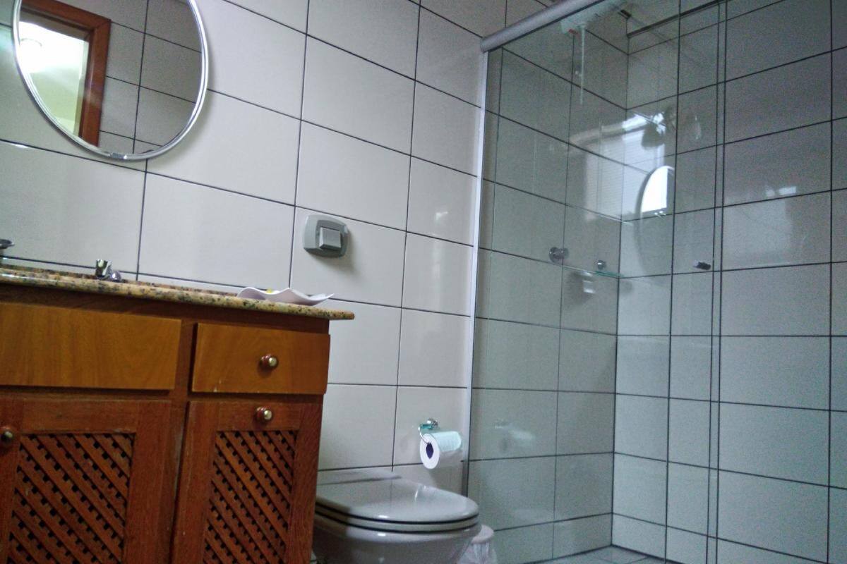 Une salle de bain comprenant des toilettes, un miroir, un lavabo avec un meuble en bois, et un espace douche.