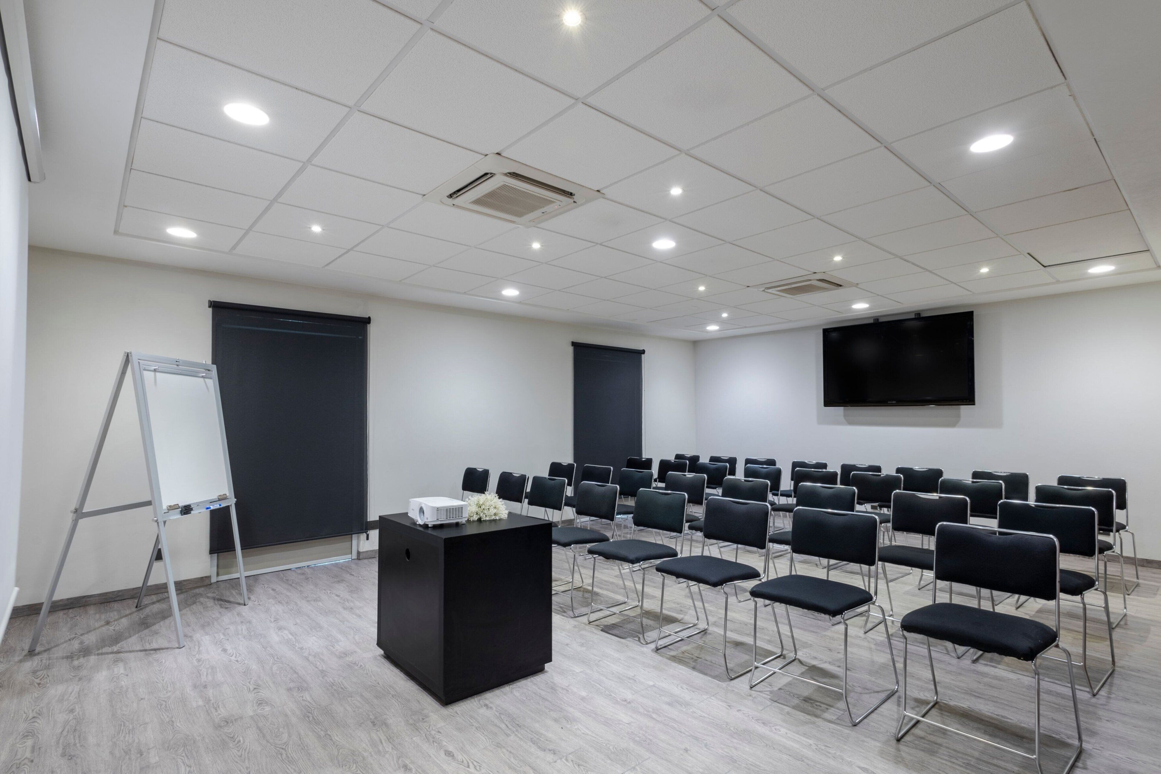 Ein Konferenzraum mit Projektor, Rednerpult, Reihen von Stühlen, einer Tafel und einer großen Leinwand.