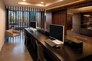 A modern office space with two desks, chairs, and a sofa.