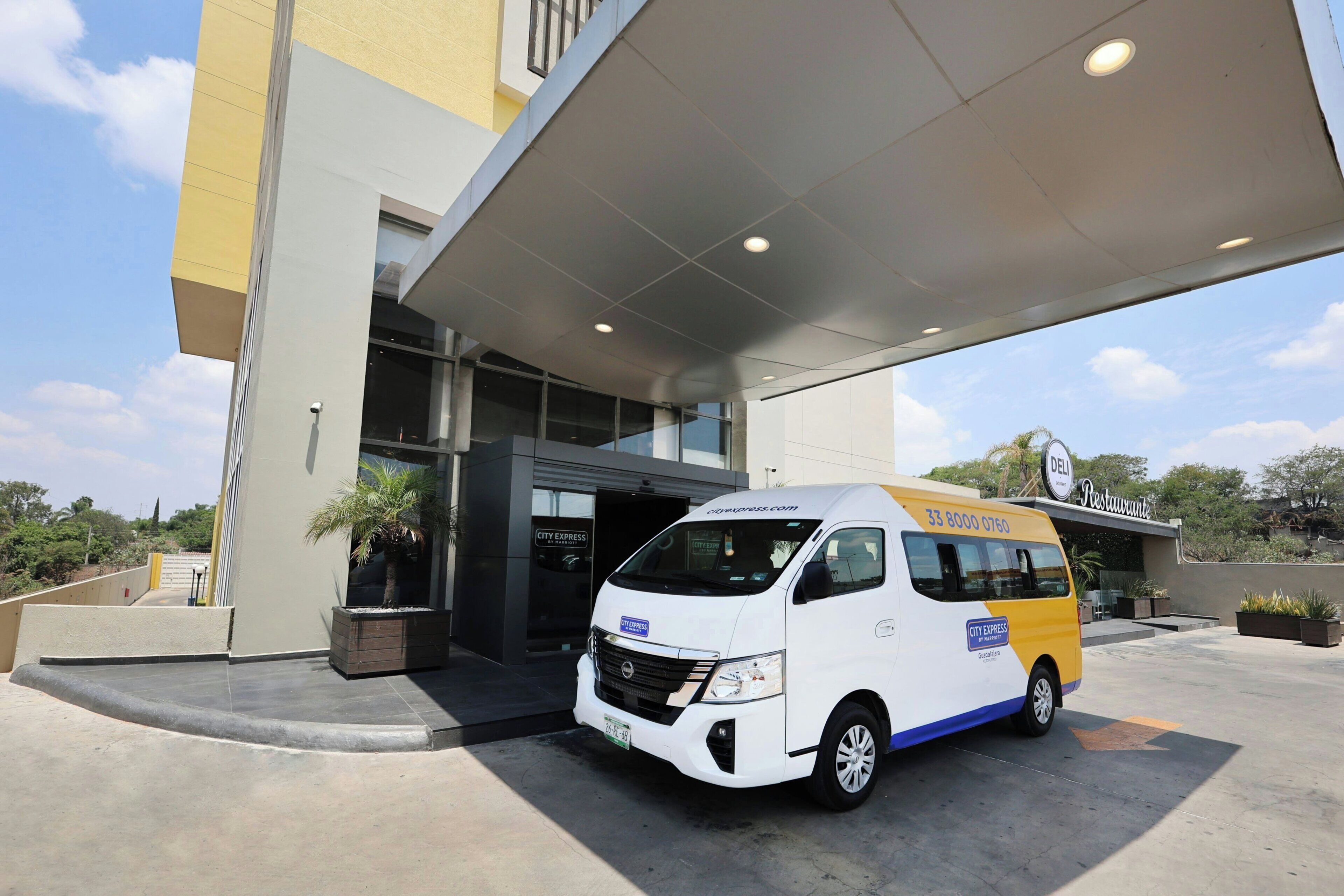 Una camioneta blanca y amarilla estacionada frente a un edificio con un letrero que dice 'CITY EXPRESS'.