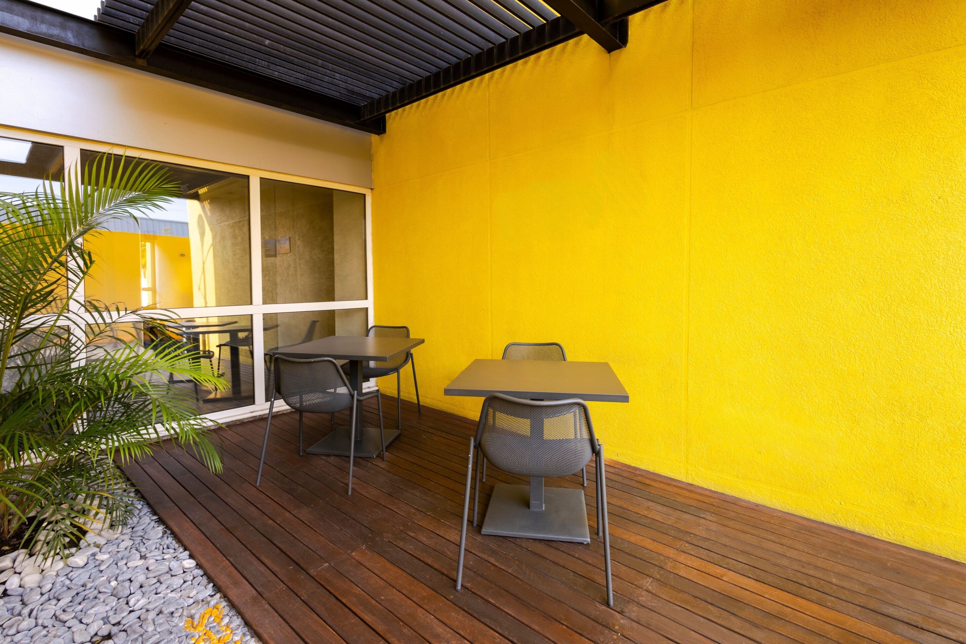 Un patio al aire libre con cubierta de madera, dos mesas y sillas.