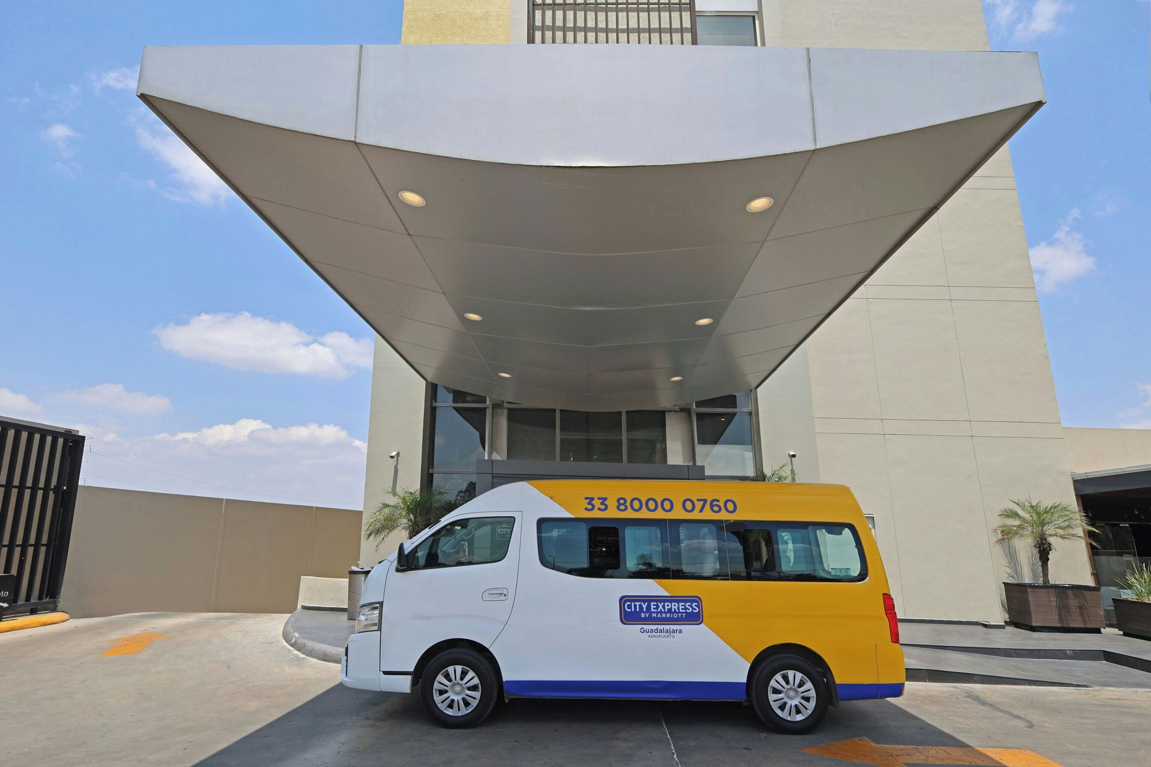 Harriott van -merkkinen City Express -pakettiauto on pysäköity modernin näköisen rakennuksen eteen, ja taivas on kirkas.